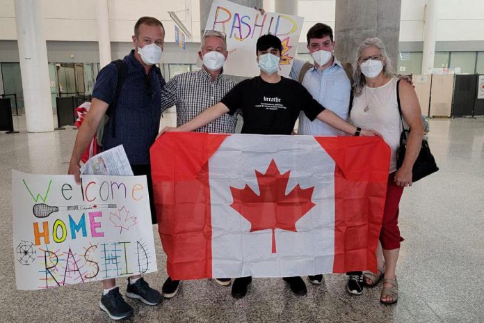 An 18-year-old Rashid holds the Canadian flag after arriving at Toronto's Pearson International Airport on June 23, 2022, where he was welcomed to his new home by his sponsors (left to right) Michael VanDerHerberg, Dave McNab, Matt Park, and Kristy Hiltz. (Photo courtesy of Dave McNab)