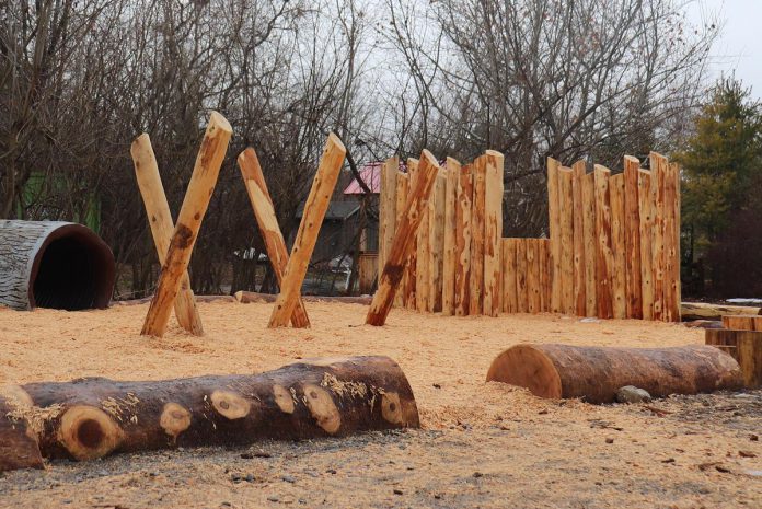 Cedar logs are used to create a balancing structure at Ecology Park's new naturalized playscape. A puppet theatre is seen in the background. (Photo: Lili Paradi / GreenU