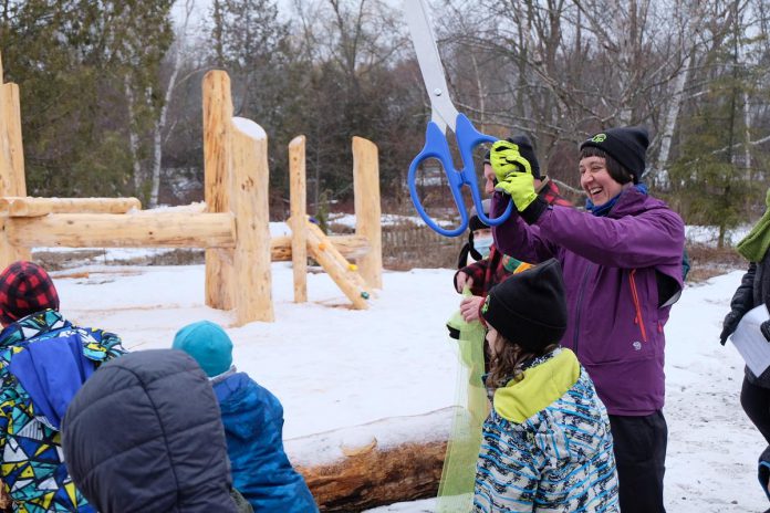 GreenUP executive director Tegan Moss cuts the ribbon to signify the opening of the Peterborough's first naturalized playscape on public grounds at Ecology Park on March 31, 2023, to the excitement of the many children eager to try the playscape.  (Photo: Lili Paradi / GreenUP)
