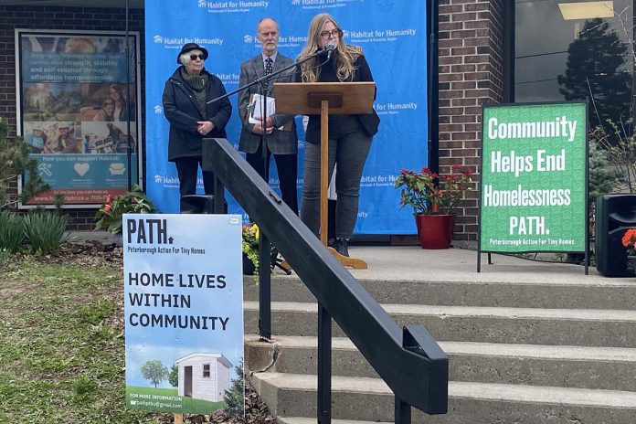 Habitat for Humanity Communications and Donor Services Manager Jenn MacDonald spoke from the podium outside Habitat for Humanity's Milroy Drive location on April 25, 2023, setting the stage for a joint announcement from Habitat for Humanity and Peterborough Action for Tiny Homes (PATH). (Photo: Paul Rellinger / kawarthaNOW)
