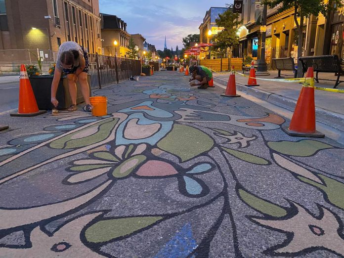 Nuin-Tara Morin and assistant Chris Boyd complete the "Nothing Out of Reach" road mural in July 2022 as part of the City of Peterborough's 2022 Renaissance on Hunter public art project. Nuin-Tara Morin is one of the four artists in the 2022 program who will serve as mentors for 10 local artists to be selected for the 2023 Road Mural Mentorship Program. (Photo: City of Peterborough Public Art Program / Facebook)