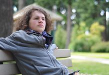 Teenage boy sitting on a park bench. (Stock photo)