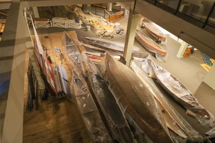 An overhead view of the lobby at The Canadian Canoe Museum's Monaghan Road location, showing canoes packed in bags, exhibit signage removed from the walls, and small artifacts gathered from exhibits, all in preparation for the museum's move to its new home currently under construction at the water's edge on Little Lake in the heart of Peterborough. (Photo courtesy of The Canadian Canoe Museum)