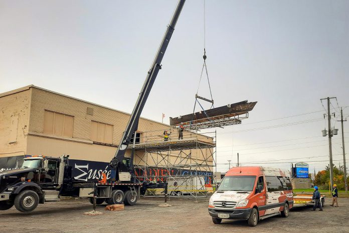 A crane lifts the heaviest canoe in The Canadian Canoe Museum collection out of a second-floor hatch and onto a trailer for transport at the museum's Monaghan Road location during one of the museum's "Big Lifts", in preparation for the museum's move to its new home currently under construction at the water's edge on Little Lake in the heart of Peterborough. (Photo courtesy of The Canadian Canoe Museum)