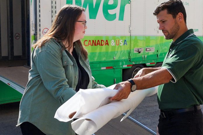 Canadian Canoe Museum collections intern Natalie Short passes wrapped paddles to an employee of McWilliams Moving and Storage in Peterborough, which as the lead sponsor and official mover of the museum's collection, which will soon embark on an almost three-kilometre portage to its new waterfront home on Ashburnham Drive by the shores of Little Lake. (Photo courtesy of The Canadian Canoe Museum) 