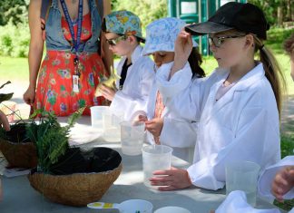 Young students during the first day of the annual Peterborough Children's Water Festival on May 30, 2023 donned lab coats and investigated various tests on liquids to understand the concept of acidity in water. (Photo: Lili Paradi / GreenUP)