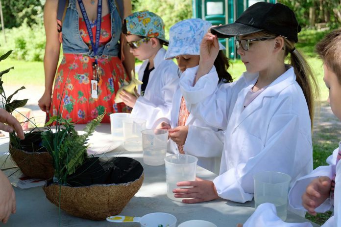 Young students during the first day of the annual Peterborough Children's Water Festival on May 30, 2023 donned lab coats and investigated various tests on liquids to understand the concept of acidity in water. (Photo: Lili Paradi / GreenUP)