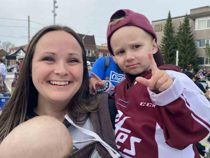 Bennett Hildenbrand, with help from his mom Emily, was in full game mode during the Peterborough Petes community watch party at Quaker Foods City Square in downtown Peterborough on May 19, 2023. (Photo: Paul Rellinger / kawarthaNOW)