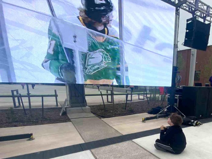 Why fight the crowd when you can sit right up front? This young Peterborough Petes fan got up close and personal with the 16-foot screen during the Peterborough Petes community watch party held held May 19, 2023 at Quaker Foods City Square in downtown Peterborough.  (Photo: Paul Rellinger / kawarthaNOW)