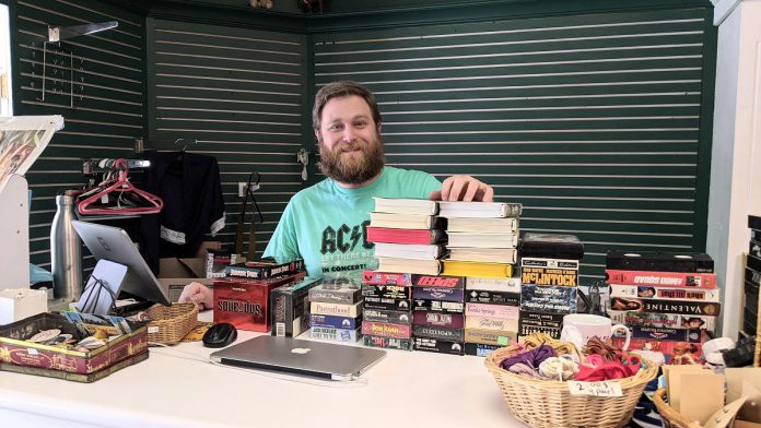KitCoffee owner Helen McCarthy's partner Zack Cruise with some of the inventory at Kit's Emporium, a new thrift store located at 404 George Street North and connected on the inside to KitCoffee at 144 Hunter Street West. (Photo: Bruce Head / kawarthaNOW) 