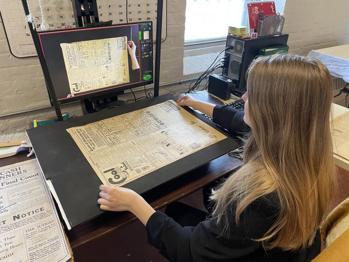 Kawartha Lakes Museum & Archives project staff Jenna Locke scanning an issue of The Lindsay Post for upload to the Internet Archive. (Photo courtesy of Kawartha Lakes Museum & Archives)