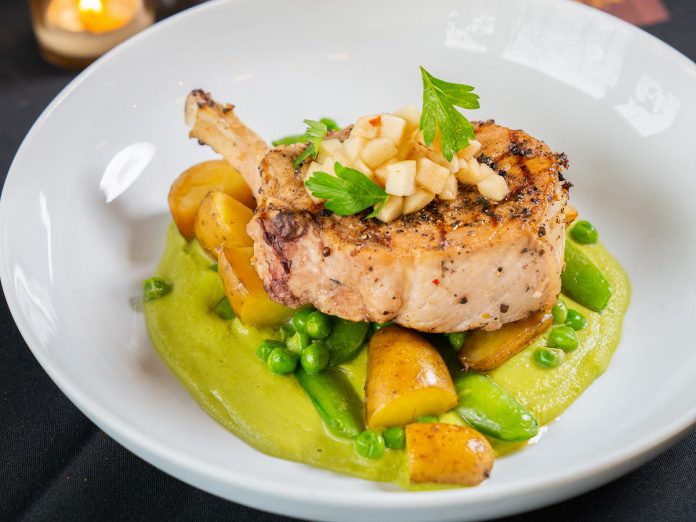 The cider-brined grilled pork loin at Rare Restaurant and Bar is completed with peas purée, sugar snap peas, apple gastric, and confit fingerlings.  (Photo courtesy of Rare Restaurant and Bar)