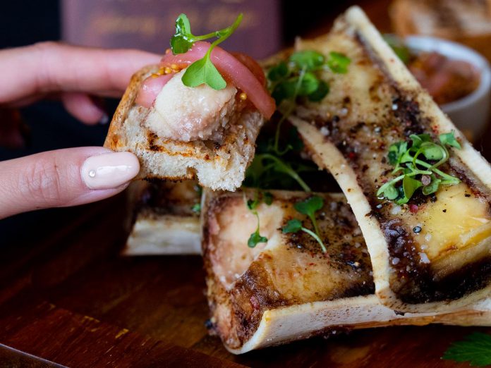 The new menu at Rare Restaurant and Bar features such French cuisine-inspired dishes like roasted bone marrow. This two-piece dish includes herb salad, pickled onions, capers, and  sprouted mustard. (Photo courtesy of Rare Restaurant and Bar)