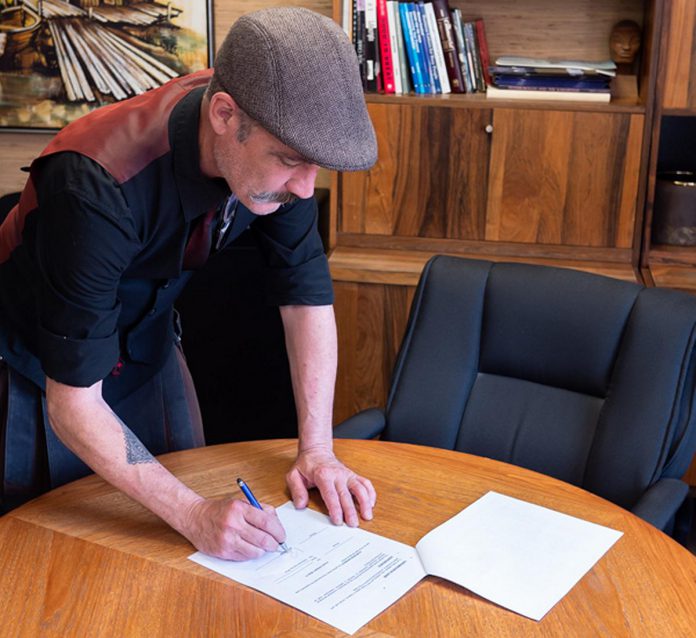 The Theatre On King's artistic director Ryan Kerr signs a two-year lease for the organization's 171 King Street location. The future of Peterborough's only black-box theatre was thrown into doubt earlier this spring when Peterborough city council decided against providing any funding, until the Peterborough community stepped up with donations. (Photo courtesy of The Theatre On King)