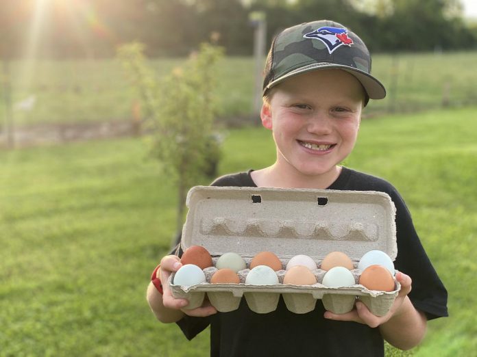 Ashley Foreman and Chris Duff's eight-year-old son James with a carton of Duff Acres eggs. Though the couple began by just selling the eggs and produce they were unable to consume within their own family, they now can't keep up with the demand from the community. (Photo: Ashley Foreman) 