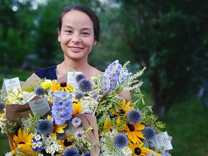 Summer Roads Flower Company owner Beatrice (Bea) Chan with some of the bouquets she sells from the seasonal flowers she grows on Summer Roads Farm between Lakefield and Young's Point. The business arose from a restoration project that Bea began five years ago on her parents' property, when she transformed compact driveway fill into a regenerative pasture. (Photo courtesy of Bea Chan)