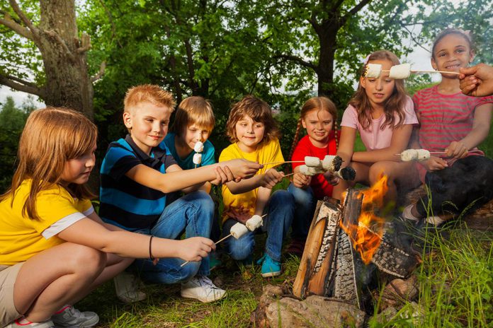 A group of children roasting marshmallows over a campfire. (Stock photo)