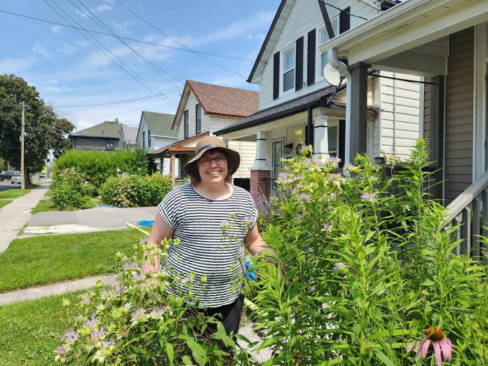 Peterborough resident Cass Stabler in her front yard rain garden surrounded by wild bergamot, a native plant that flowers from mid to late summer and is adored by many native pollinators. Stabler applied for and received a rain garden subsidy from the City of Peterborough in 2020, the first year the program was offered. (Photo: Hayley Goodchild / GreenUP)
