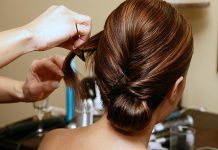 A hair stylist works on a woman's hair. (Stock photo)