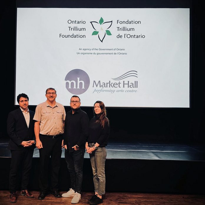 Market Hall board chair Joe Grant, Peterborough-Kawartha MPP Dave Smith, Market Hall general manager Chad Hogan, and Market Hall board member and artist manager Jennifer Cavanagh on stage at the Charlotte Street venue on August 30, 2023 in front of the state-of-the-art projector funded by a $149,100 capital grant from the Ontario Trillium Foundation. (Photo courtesy of Market Hall) 