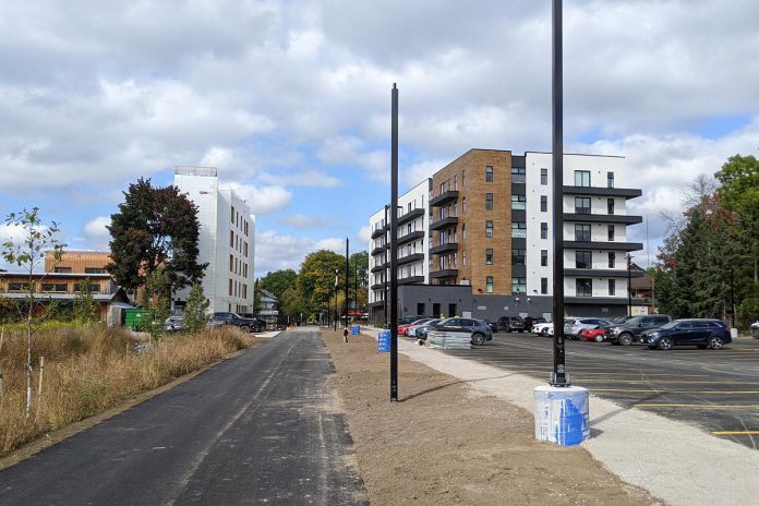 Looking north along the Rotary Greenway Trail in Peterborough's East City to two of the buildings in Ashburnham Realty's residential-commercial development. The city's committee of adjustment approved an increase of a third residential building to be constructed along the trail to the south from three to six storeys, drawing the ire of some neighbouring residents. Developer Paul Bennett says the height of the third building is doubling as a fourth building is no longer going ahead, and the total number of units in the development remains the same. (Photo: Bruce Head / kawarthaNOW)