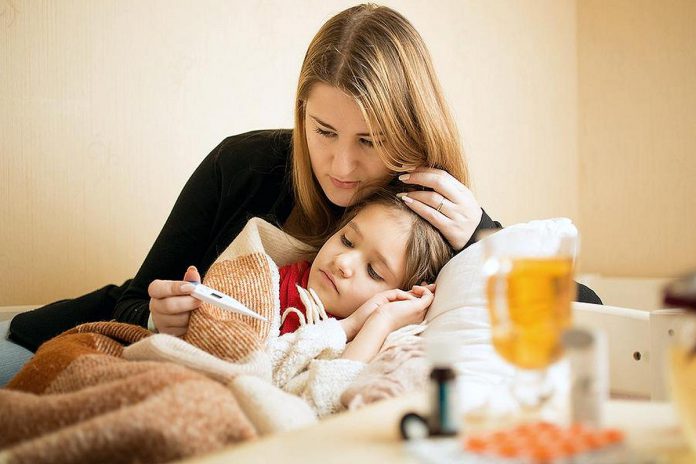 A mother taking the temperature of a sick child. (Stock photo)