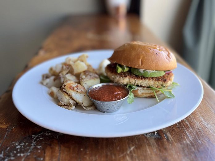 The Vine in Peterborough offers vegetarian, vegan, and pescatarian fare, including the salmon burger featuring a salmon patty, remoulade, avocado, red onion, and arugula on a brioche bun. The dish comes with a side of potato wedges (pictured), salad, or soup. (Photo courtesy of The Vine)