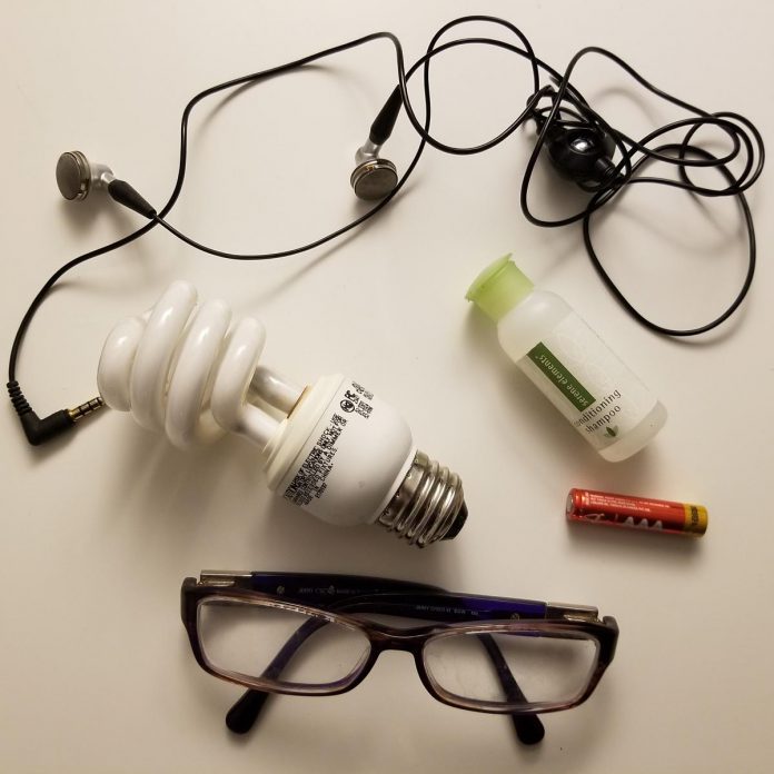 A collection of small items you may not know you can recycle or donate, including glasses, a fluorescent lightbulb, earbuds, a travel shampoo bottle, and a battery. (Photo: Adeilah Dahlke / Jigsaw Organizing Solutions)