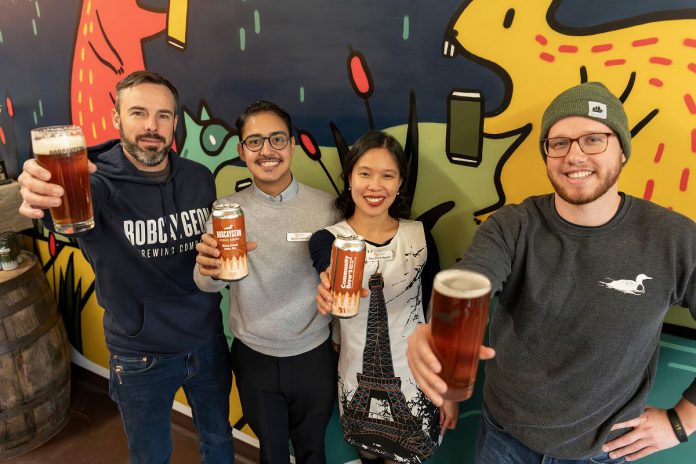 Reggie Maranda of Mcthirsty's Pint (left) and Garrett Bulmer of Bobcaygeon Brewing Company (right), pictured with Mauricio Interiano and Paris Nguyen of the New Canadians Centre, raise a pint of West Coast Pale Ale, the third beer in the 'Community Brew' series, with a portion of sales to be donated to New Canadians Centre. (Photo: Luke Best / Bobcaygeon Brewing Company)