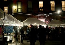 The Commerce Building Courtyard in downtown Peterborough will be transformed into a festive market on December 1, 2023 for the Neighbourhood Holiday Market organized by The Neighbourhood Vintage in partnership with First Friday Peterborough. The evening event during the First Friday art crawl features work from 20 local artists and artisans, live music performances, and food and drink. Pictured is the December 2022 market. (kawarthaNOW screenshot of First Friday Peterborough video)