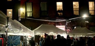 The Commerce Building Courtyard in downtown Peterborough will be transformed into a festive market on December 1, 2023 for the Neighbourhood Holiday Market organized by The Neighbourhood Vintage in partnership with First Friday Peterborough. The evening event during the First Friday art crawl features work from 20 local artists and artisans, live music performances, and food and drink. Pictured is the December 2022 market. (kawarthaNOW screenshot of First Friday Peterborough video)