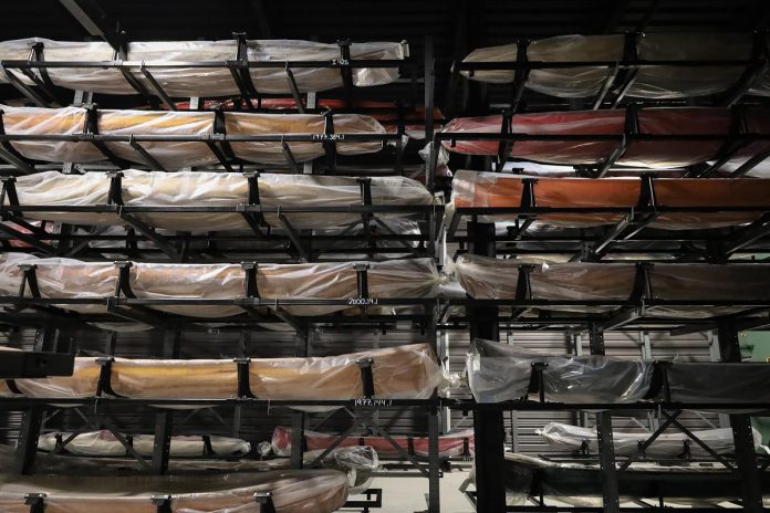 Canoes temporarily wrapped in protective plastic and of various sizes and colours line the racks of the Collection Hall in the new Canadian Canoe Museum. Each canoe or kayak is placed on the racking, bow-to-stern, facing towards the atrium's large windows. (Photo courtesy of The Canadian Canoe Museum)