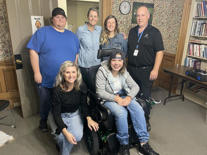 Fifteen-year-old Kaydance (in wheelchair) stops by Five Counties' Seating and Mobility Clinic with her mom April (standing, second from right) to get her chair adjusted. Also pictured are (standing, from left) Five Counties technician Luke, occupational therapist Kate Jaboor, and seating and mobility consultant Stewart from Motion Peterborough. Crouched beside Kaydance is Five Counties physiotherapist Ange Harrison. (Photo courtesy of Five Counties Children's Centre)