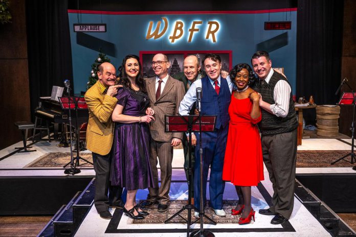 New Stages artistic director Mark Wallace (third from left) is directing "It's a Wonderful Life: A Live Radio Play" at Market Hall Performing Arts Centre in downtown Peterborough until December 17, 2023. Musical director Gabriel Vaillant (far right) plays piano during the performance, with actors (from left to right) Brad Brackenridge, Megan Murphy, Kerry Griffin, M. John Kennedy, and Ordena Stephens-Thompson performing all the characters from the movie and also creating all of the sound effects. (Photo: Dahlia Katz)