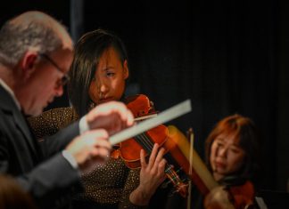 As the final concert of her six-concert music series "Travel by Sound", violinist Victoria Yeh (middle) will be performing a new "Timeless" concert at Peterborough's Market Hall on the winter solstice on December 21, 2023 alongside conductor John Kraus (left) and concertmaster Natalie Wong (right). The evening will feature Yeh performing music spanning classical and jazz fusion genres, including several of her original compositions, supported by 15 other musicians. (Photo: Trevor Hesselink / Groundswell Photography)