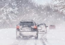 Three cars on a snow-covered road during a winter blizzard. (Stock photo)