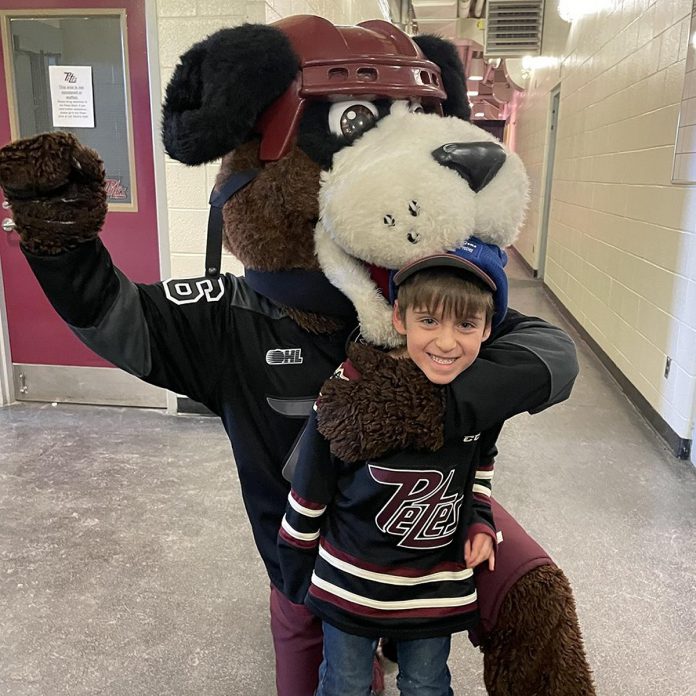 It wasn't a bear hug, but maybe a 'ruff-ing' the player penalty. Whatever it was, Peterborough Petes mascot Roger gives a friendly welcome to Five Counties kid Deacon, whose family did the ceremonial pre-game puck drop prior to the Petes Family Day home game on February 19, 2024. (Photo courtesy of Five Counties Children's Centre)