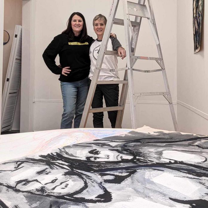 The late Ann Cossar's former student Cydnee Hosker (right) and artist Julie Francey installing the "Life Studies and Other Works by Ann Cossar" exhibit at Francey's Studio 12 in Peterborough's Commerce Building. The exhibit will launch during the First Friday Peterborough Art Crawl on March 1, 2024 and will then be available by appointment only until March 31. (Photo courtesy of Cydnee Hosker)