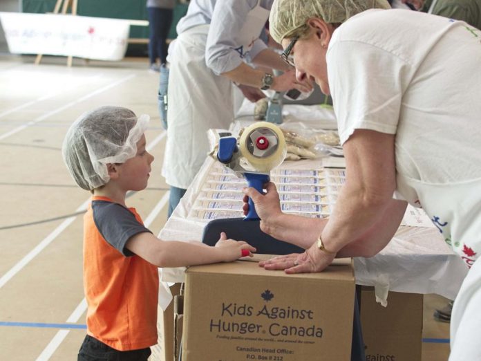 A child helps a volunteer pack meals during a past One Million Meals Peterborough event in support of Kids Against Hunger Canada. (Photo: One Million Meals Peterborough / Facebook)