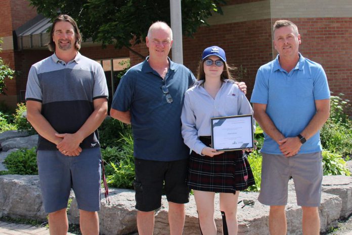 Eliza Graham (holding plaque) was the 2022 recipient of the H.O.P.E. Steve Montador Bursary. Also pictured, from left to right, are Mike Martone of H.O.P.E., Eliza's father David, and Chad Cavanagh of H.O.P.E. (Photo: Vince Bierworth / GPHSF, Your Family Health Team Foundation)