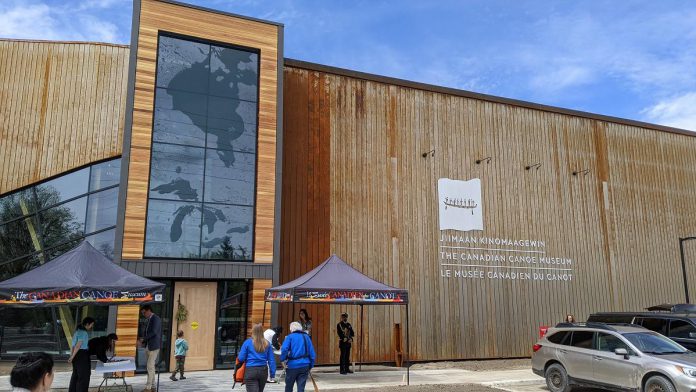 The new Canadian Canoe Museum at 2077 Ashburnham Drive on the shores of Little Lake in Peterborough, which officially opens to the public on May 13, 2024, hosted a grand opening celebration on May 11. Pictured is the main entrance to the museum with the feature window showing Hudson Bay and the Great Lakes and the museum's sign in Anishnaabemowin, English, and French, representing the languages of those who share the canoe's history. (Photo: Bruce Head / kawarthaNOW)