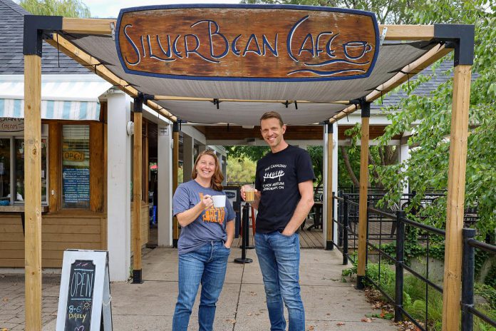 Canadian Canoe Museum executive director Carolyn Hyslop and Silver Bean Café owner Dan Brandsma celebrated their new partnership in 2022 by donning each other's T-shirts and raising a cup of coffee to their future together. The Silver Bean Café at the new Canadian Canoe Museum at 2077 Ashburnham Drive on the shores of Little Lake opens along with the new museum on May 13, 2024. (Photo courtesy of The Canadian Canoe Museum)