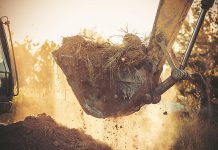 An excavator moving soil during home construction. (Stock photo)