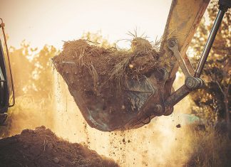 An excavator moving soil during home construction. (Stock photo)