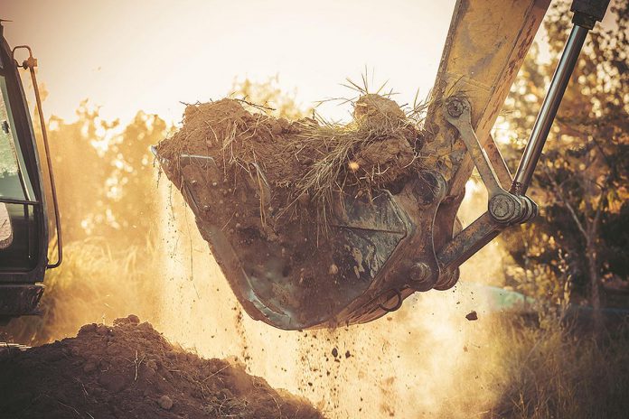 An excavator moving soil during home construction. (Stock photo)