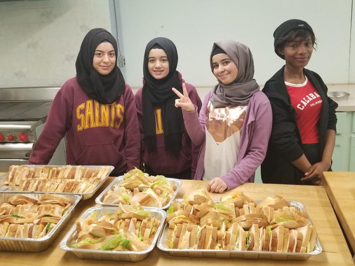 In 2024, the New Canadians Centre is celebrating 45 years of supporting newcomers to the Peterborough and Northumberland areas, including helping them become leaders in the community. Pictured in 2018 are Noor, Rushen, Simav, and Aicha, four newcomer youth from Syria and the Ivory Coast who came together as a group to volunteer to make food for clients of the Warming Room, which became One City Peterborough. Acknowledging the support their families received in their times of need, the girls felt it important to pay it forward by helping others in need. (Photo courtesy of New Canadians Centre)