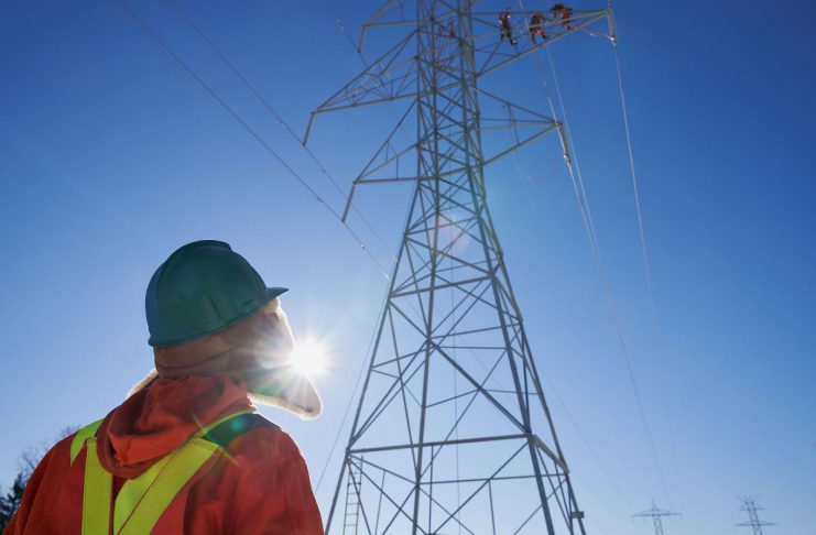 Hydro One seeking OEB approval to proceed with construction of new transmission line between Clarington and Peterborough Hydro One worker looking up at other workers on a transmission tower. (Photo: Hydro One)