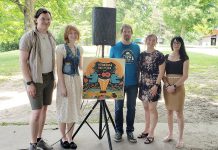 Musician Calvin Bakelaar (left) was named as the Peterborough Folk Festival's 2024 Emerging Artist at an event at Nicholls Oval Park on June 19, 2024. Also pictured, from left to right, are artist Brooklin Stormie with her festival poster design, festival board chair Rob Davis, board secretary Rebecca Schillemat, and board treasurer Krissy Edwards. (Photo: Jeannine Taylor / kawarthaNOW)