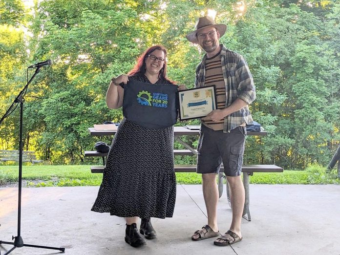 Dylan Radcliffe accepts a Shifting Gears workplace award on behalf of Engage Engineering from Peterborough GreenUP's Ashley Burnie during a 20th anniversary celebration at Nicholls Oval Park on May 31, 2024, which saw six businesses or organizations receive the awards. (Photo courtesy of GreenUP)