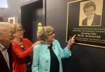 Beth McMaster, who was instrumental in the founding of Showplace Performance Centre in downtown Peterborough in the early 1990s and served as the inaugural chair of the non-profit organization's board of directors, points to the plaque honouring her contribution that was unveiled in the lobby of the performing arts venue on June 11, 2024. (Photo: Paul Rellinger / kawarthaNOW)